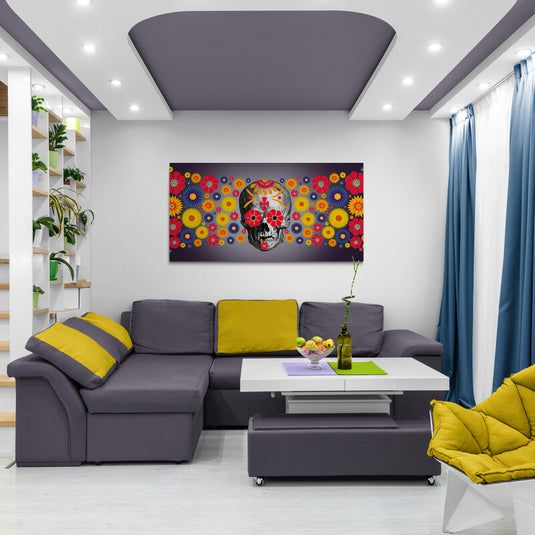 Calavera decorada con patrones y rodeada de flores coloridas sobre fondo oscuro.