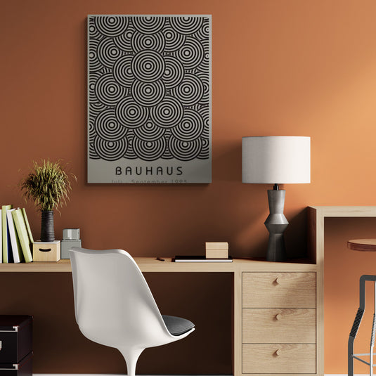 Cuadro Bauhaus en blanco y negro con patrones circulares en una oficina moderna con paredes naranja y decoración minimalista.