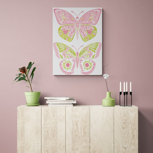 Cuadro de mariposas rosa y verde sobre aparador de madera y pared rosa