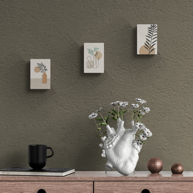 Tríptico de lienzos minimalistas con diseños botánicos en pared texturizada