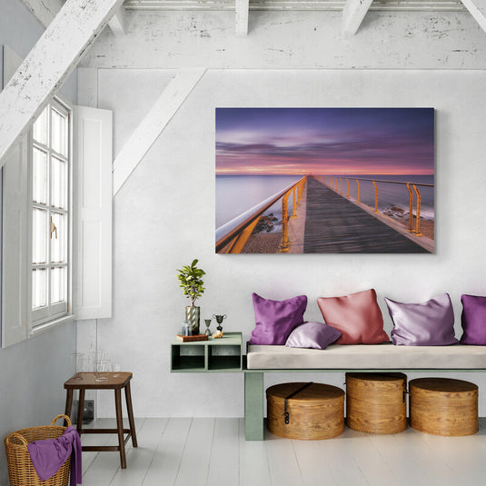 Fotografía de larga exposición de un muelle al amanecer con barandillas amarillas y cielo colorido