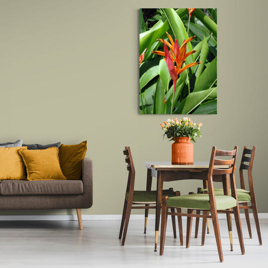 Fotografía de heliconia con pétalos naranjas y rojos entre hojas verdes