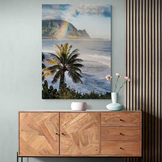 Palmera tropical frente a océano con arcoíris y montañas al fondo