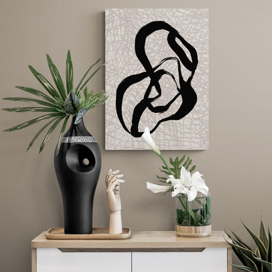 Arte abstracto con trazos negros sobre fondo texturizado decorando una pared beige con plantas y esculturas.