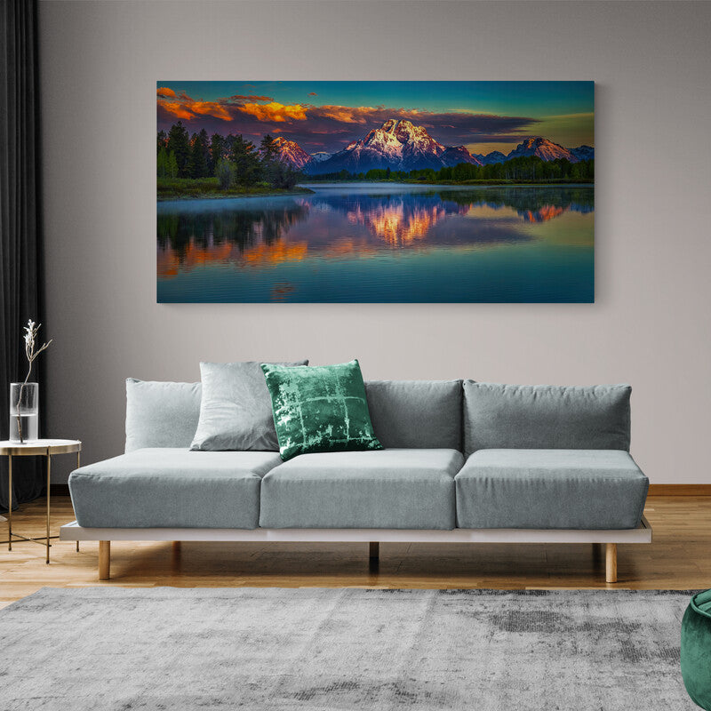 Fotografía artística de un vasto lago reflejando montañas y pinos bajo un cielo azul de atardecer con tonos de naranja y amarillo