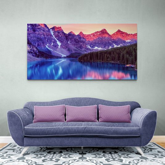 Fotografía artística de un lago azul con montañas moradas, toques rosados y pinos verdes en un vibrante paisaje natural