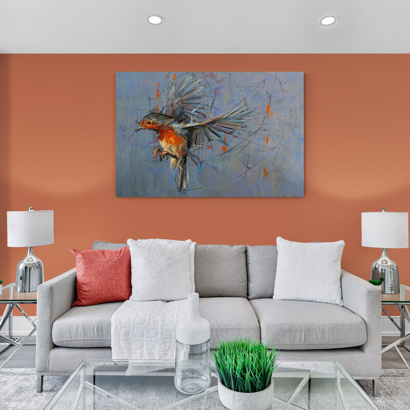 Cuadro decorativo con pajarito en vuelo en tonos naranja y grises sobre fondo azul gris, acompañado de destellos de colores desprendiéndose del ave