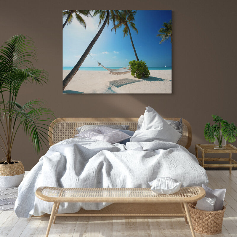 Hamaca vacía entre dos palmeras en una playa desierta con cielo claro